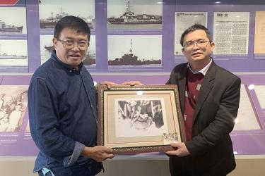 Ông Trần Thọ Phi Hổ (trái) tặng những bức ảnh quý chụp ở đảo Hoàng Sa cho ông Lê Tiến Công - phó giám đốc phụ trách Nhà trưng bày Hoàng Sa
