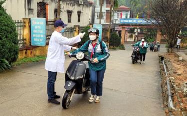 Students of the Quang Trung Secondary School in Dong Tam ward of Yen Bai city have their temperature checked before entering classrooms.